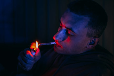 Portrait of a man in neon who smokes a joint. Guy smokes joint, marijuana, drugs cbd and thcの写真素材