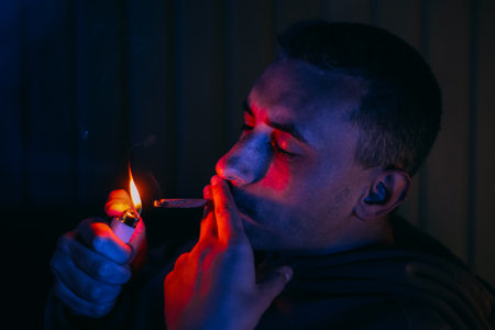 Portrait of a man in neon who smokes a joint. Guy smokes joint, marijuana, drugs cbd and thcの写真素材