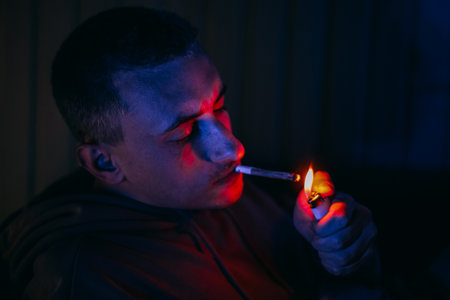 Portrait of a man in neon who smokes a joint. Guy smokes joint, marijuana, drugs cbd and thcの写真素材