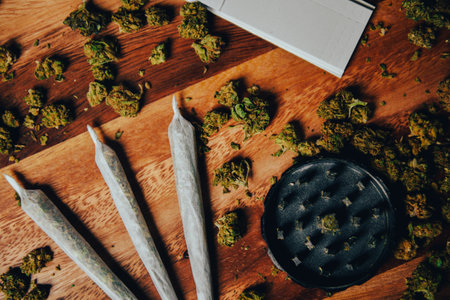 Marijuana shoals on a wooden table. Grinder, filter paper and cigarettes. Drugs on a table background with cbd or thc, indica or sativa buds.の写真素材
