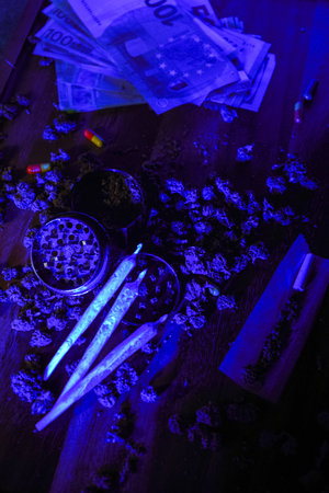 Marijuana buds with drugs, cbd and thc. Grinder and joints, euro money, dollars. Dirty business, dealer house. Blue neon and pills, ecstasy, mdma, amphetamineの写真素材