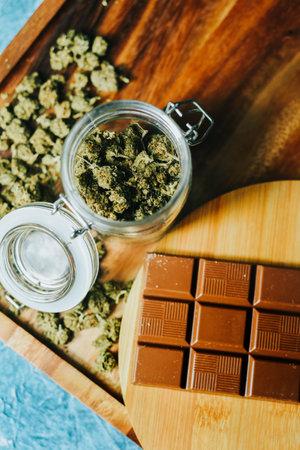Chocolate with marijuana on the background of a wooden table and marijuana cones. CBD and THC, sativa and indica. marijuana grass in foodの写真素材
