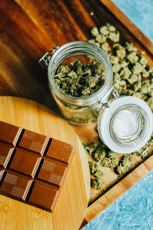 Chocolate with marijuana on the background of a wooden table and marijuana cones. CBD and THC, sativa and indica. marijuana grass in foodの写真素材