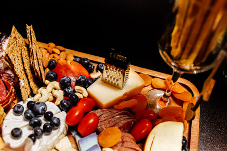 Cheese platter, cheese board meat and board. Vegetables and fruits with cheese and chocolate, prosciutto and salami with bread. Big board of snacks for the party.の写真素材