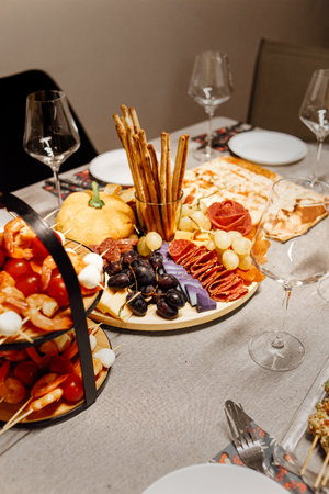 Cheese platter, cheese board meat and board. Vegetables and fruits with cheese and chocolate, prosciutto and salami with bread. Table with wine glasses, shrimp dinnerの写真素材
