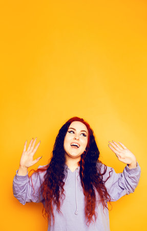 A girl with frizzy and split ends on an orange background in a blue sweatshirt poses. Beautiful brunette. smile happyの写真素材