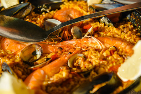 Traditional Paella served at restaurant seafood paella in the fry pan with a huge iron spoon, shrimp and mussels, lemonの写真素材