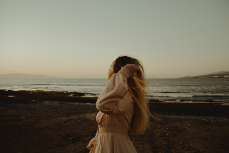 Girl on the beach with long hair, summer mood. Sunset, woman in a beautiful dress on vacation.の写真素材