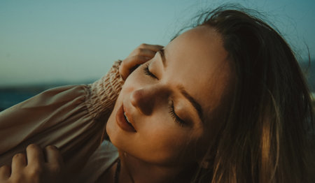 Girl on the beach with long hair, summer mood. Sunset, woman in a beautiful dress on vacation, and accessories, portrait, wind in her hairの写真素材