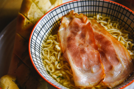 Instant pasta, Japanese and Chinese noodles. Ramen type soup in a plate with chopsticks, junk fast food. Quick-cooking pasta with baconの写真素材