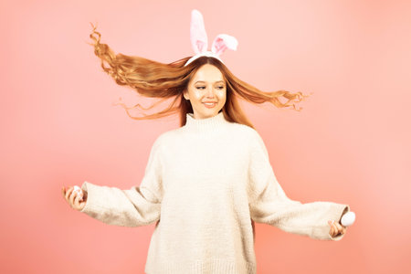 Beautiful girl in rabbit ears on a pink background laugh, Easter holidays. The woman smiles. Looks...