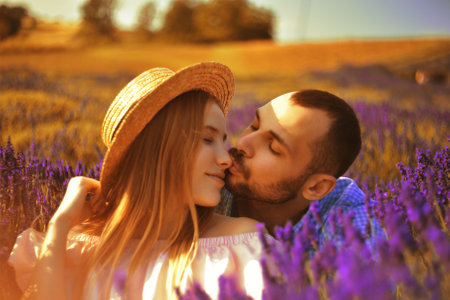 A couple in love in a field of lavender at sunset in good weather. Beautiful woman in a dress and straw panama with a man on the background of nature, love and feelings. Blue, purple lavenderの写真素材