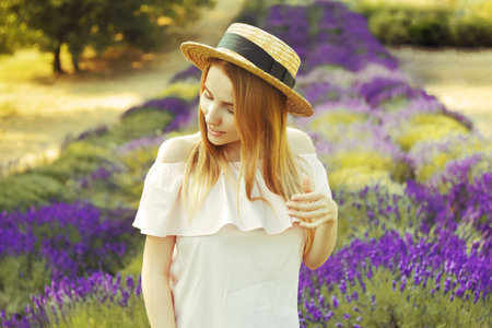 Beautiful girl on the lavender field. Beautiful woman in the lavender field at sunset. soft focus. Provence, France. A girl in pink dress and hat walking trough lavender fields and enjoys natureの写真素材