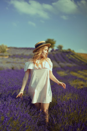 Beautiful girl on the lavender field. Beautiful woman in the lavender field at sunset. soft focus. Provence, France. A girl in pink dress and hat walking trough lavender fields and enjoys natureの写真素材