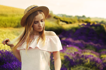 Beautiful girl on the lavender field. Beautiful woman in the lavender field at sunset. soft focus. Provence, France. A girl in pink dress and hat walking trough lavender fields and enjoys natureの写真素材
