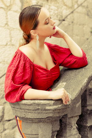 Gorgeous portrait of a beautiful woman in the old city on the stairs. Girl with makeup and hairstyle, long silver earrings posing.の写真素材