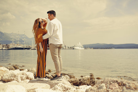 A couple walks along the beach against the backdrop of the sea and mountains. Travel of lovers. love and honeymoon. Man and girl admiring natureの写真素材