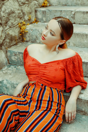 Gorgeous brunette posing lying on the stairs. Jewelry silver earrings, professional makeup, yellow suit. elegant tourist.の写真素材