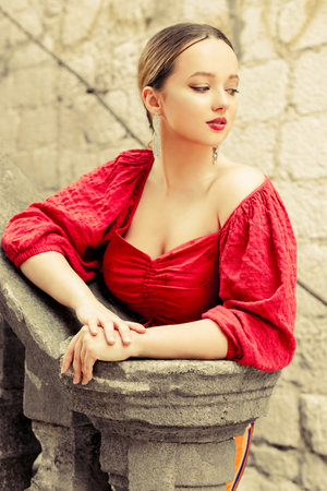 Gorgeous portrait of a beautiful woman in the old city on the stairs. Girl with makeup and hairstyle, long silver earrings posing.の写真素材