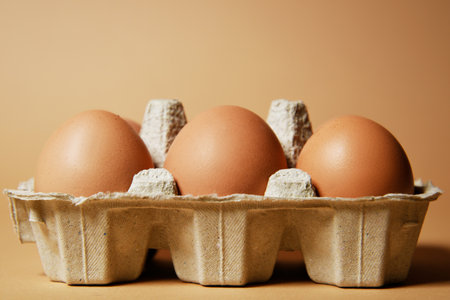 A tray with brown eggs, on a nude background, chicken feathers are flying. Eco products, nutrition, proteins and natural food.の写真素材