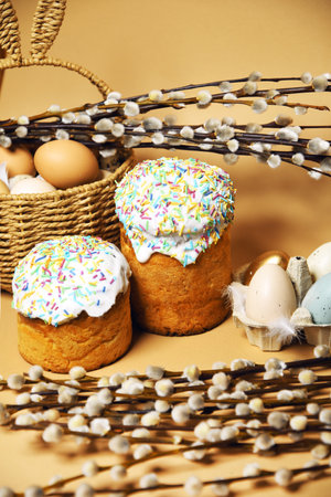 Easter holidays, pussy willow, colorful painted eggs in a tray, a basket with Easter cake on a nude background, warm. Religion and traditionの写真素材