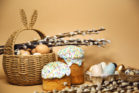 Easter holidays, pussy willow, colorful painted eggs in a tray, quail eggs in a nest, a basket with Easter cake on a nude background, warm. Religion and traditionsの写真素材
