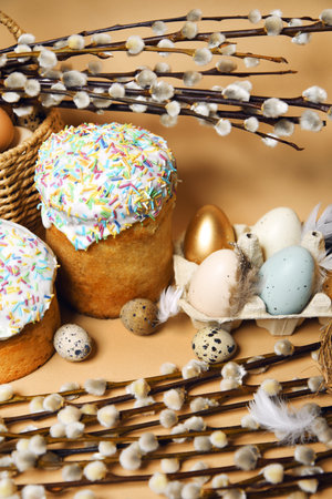 Easter holidays, pussy willow, colorful painted eggs in a tray, quail eggs in a nest, a basket with Easter cake on a nude background, warm. Religion and traditionsの写真素材