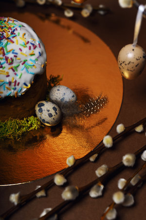 Homemade Easter cake, colored sprinkles in a shell. Quail eggs in hay, restaurant serving food. Easter and holidays on brown, Pussy willow, interesting decorations from golden eggs. restaurant servingの写真素材