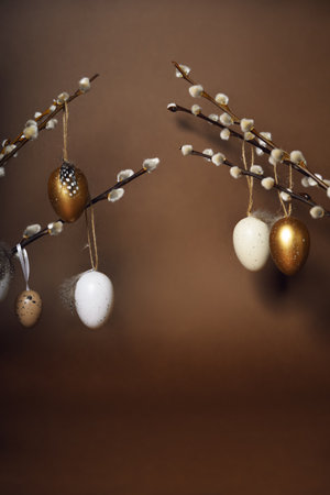Easter decorations on a brown background. Painted eggs hang on pussy willow branches. Spring is coming, place for textの写真素材