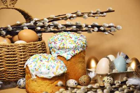 Easter holidays, pussy willow, colorful painted eggs in a tray, quail eggs in a nest, a basket with Easter cake on a nude background, warm. Religion and traditionsの写真素材