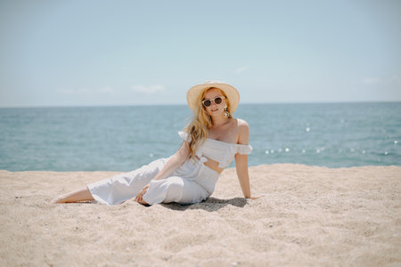 Portrait of a beautiful young woman in a hat and sunglasses on the beachの写真素材