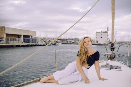 Beautiful young woman sitting on the deck of a yacht and smilingの写真素材