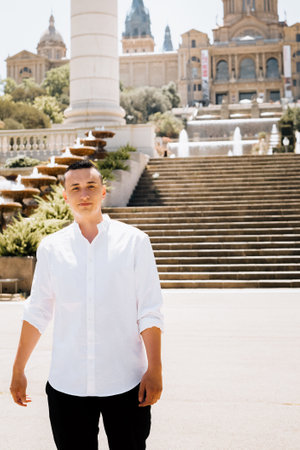 A male tourist stands against the background of Barcelona and enjoys the journey. The guy looks at the view of the city Castell de Montjuicの写真素材