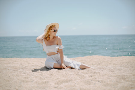 Young woman sitting on the sand by the sea. summer holidays.の写真素材
