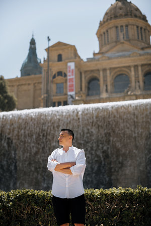 A male tourist stands against the background of Barcelona and enjoys the journey. The guy looks at the view of the city Castell de Montjuicの写真素材