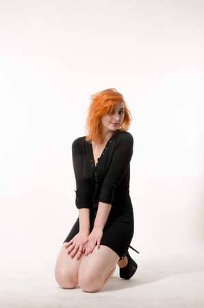 beautiful redhead girl in a black dress on a white backgroundの写真素材