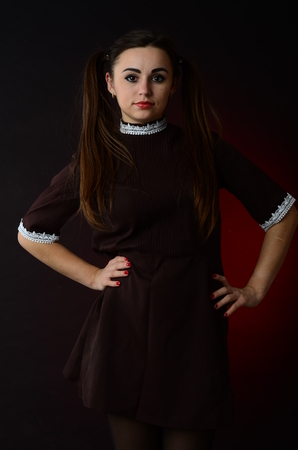 Portrait of a young girl with knife, fork and and a piece of raw meat on a plate. Girl in school uniform as killer. The image in the style of Halloweenの写真素材