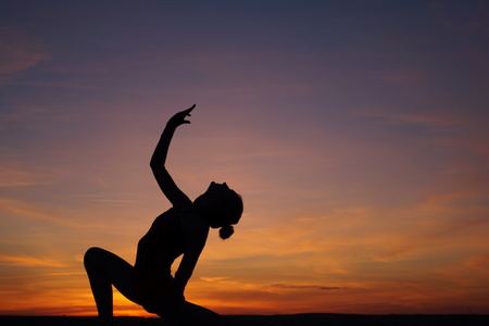 dancer in the dance does the splits in the air against the sunsetの写真素材