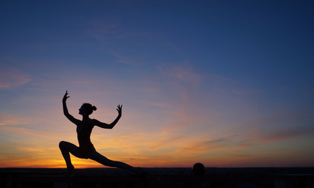 dancer in the dance does the splits in the air against the sunsetの写真素材