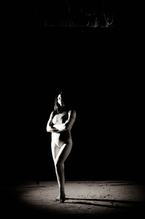 The girl with the flour on the body stretches the arms up with thrown flour on black background black and white imageの写真素材