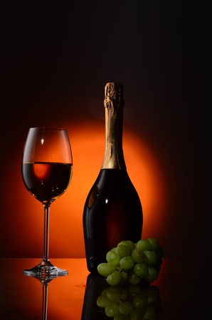 bottle of red wine, glass and grapes on dark background with place for textの写真素材
