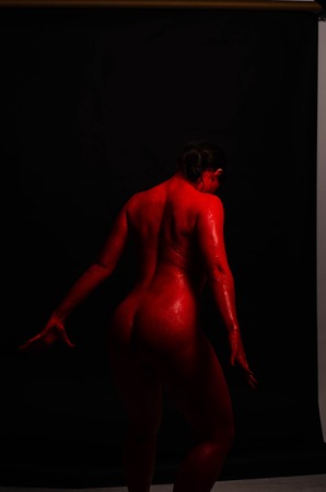 creative portrait of a young girl. The face is painted with red glitter paint. The triangle is drawn on the face. Model in profile on black backgroundの写真素材