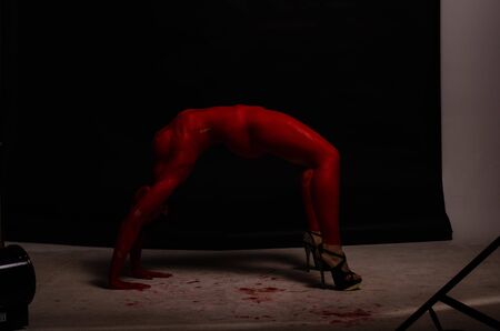 creative portrait of a young girl. The face is painted with red glitter paint. The triangle is drawn on the face. Model in profile on black backgroundの写真素材