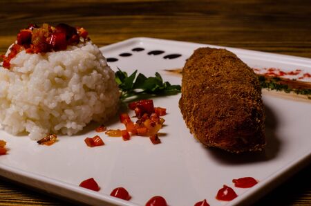 Tasty seasoned fried pork chops cooked in a spicy marinade are served with boiled potatoes, salads and sauces. Cutlets on a plate on a wooden table top view.の写真素材