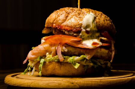 Bacon burger with beef patty on wooden table.の写真素材