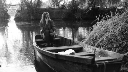 A young woman is rowing a boat on a summer dayの写真素材