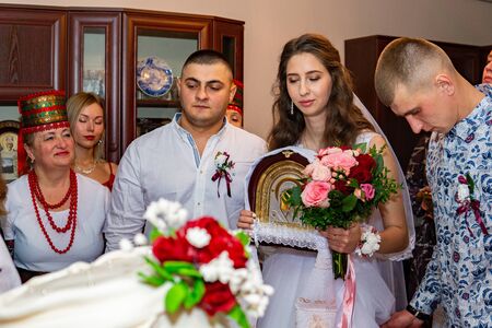 Cute wedding couple in ukrainian traditional clothes sitting on the bench in the town and spending time togetherのeditorial素材