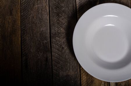 Top view of blank white dish and white tablecloth on a wood background with copy space.