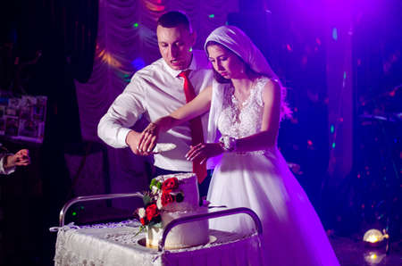 Cute wedding couple in ukrainian traditional clothes sitting on the bench in the town and spending time together Lutsk Ukraine 16.01.19.のeditorial素材