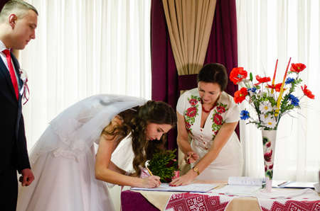 Cute wedding couple in ukrainian traditional clothes sitting on the bench in the town and spending time together Lutsk Ukraine 16.01.19.のeditorial素材